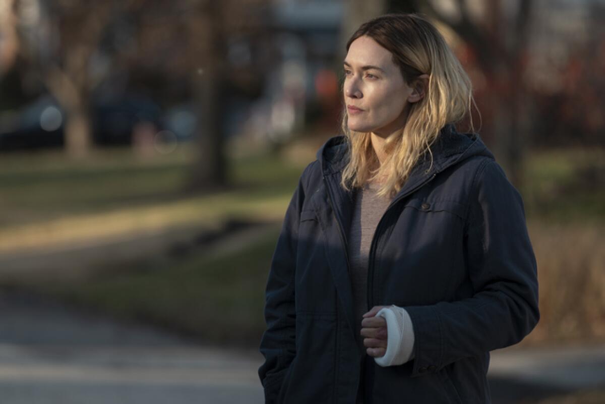 Kate Winslet in a blue jacket with a cast on her left wrist as the titular "Mare of Easttown."