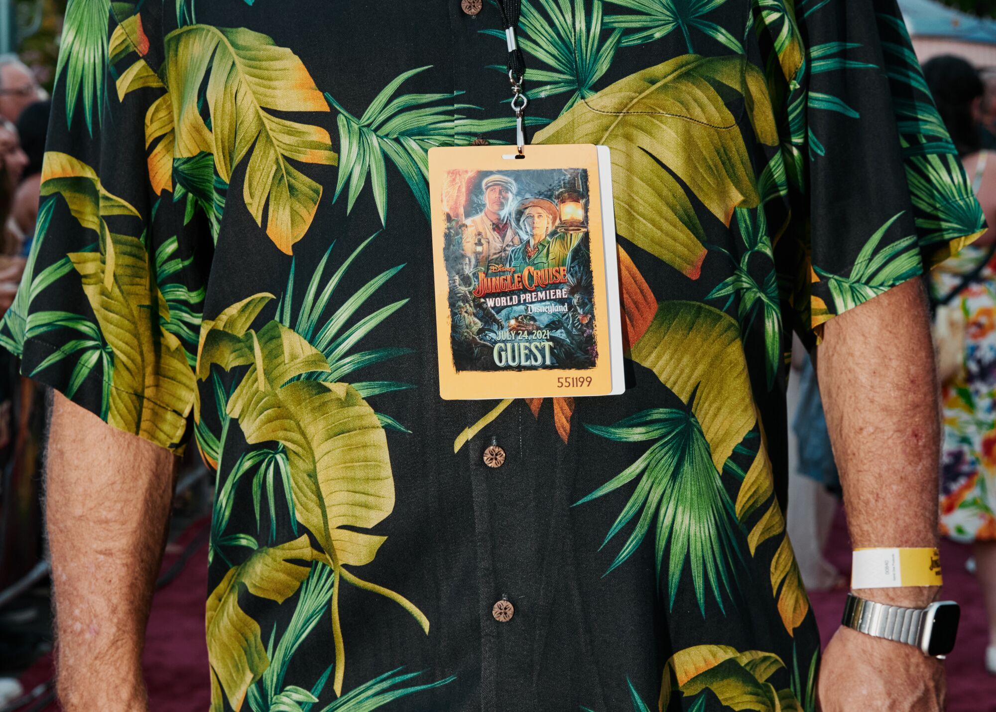 A man wears a jungle print shirt and guest badge on the red carpet.