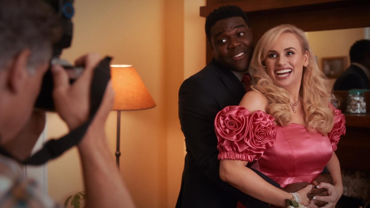 A man holds a woman in a prom dress as they are photographed in the movie "Senior Year."