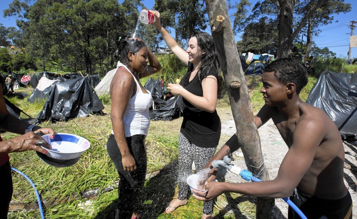Women cool down on a lot near the gleaming new Arena Corinthians soccer stadium in Sao Paulo, Brazil. About 7,000 members of the Homeless Workers' Movement are occupying the lot in a protest to demand affordable housing.