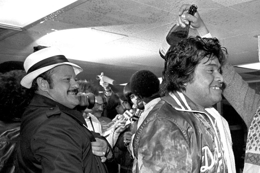 Los Angeles, CA -Baseball scout Mike Brito looks on as Fernando Valenzuela #34 of the Los Angeles Dodgers celebrates in the clubhouse after winning the 1981 World Series against the NY Yankees at Yankee Stadium. ©Photo by Jayne Kamin-Oncea
