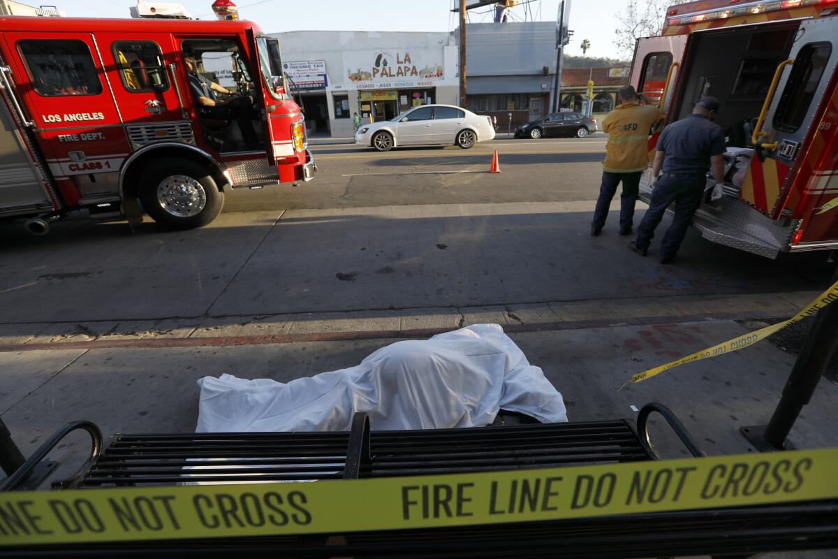 A man's covered body lies on a Highland Park sidewalk in 2018. More than 5,600 homeless people have died in L.A. County since 2013.