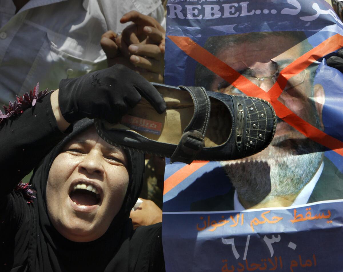 An protester hits a poster depicting Egyptian President Mohamed Morsi with a shoe in Cairo's Tahrir Square.