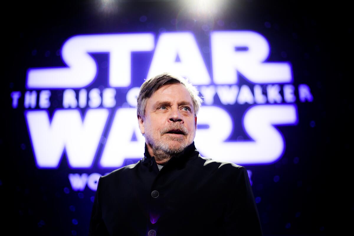Mark Hamill stands onstage in front of lighted words "Star Wars: The Rise of Skywalker."