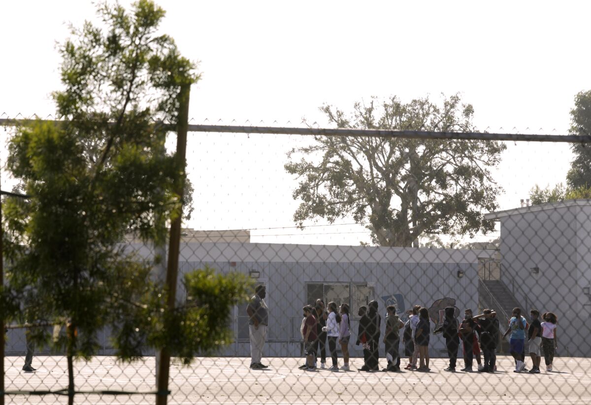 Students in a playground, seen through a chain-link fence