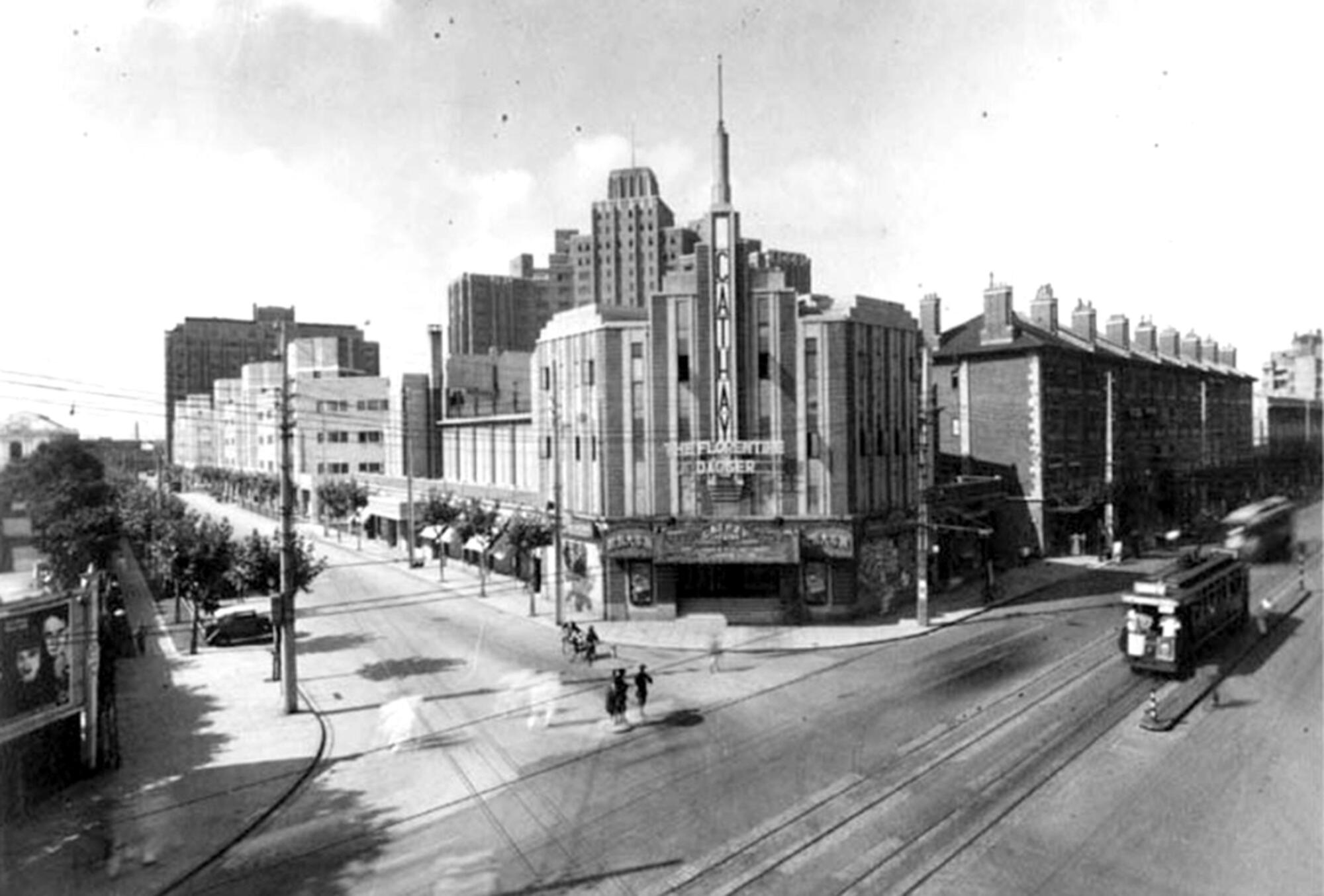 A black-and-white picture of a theater with a streetcar running nearby.