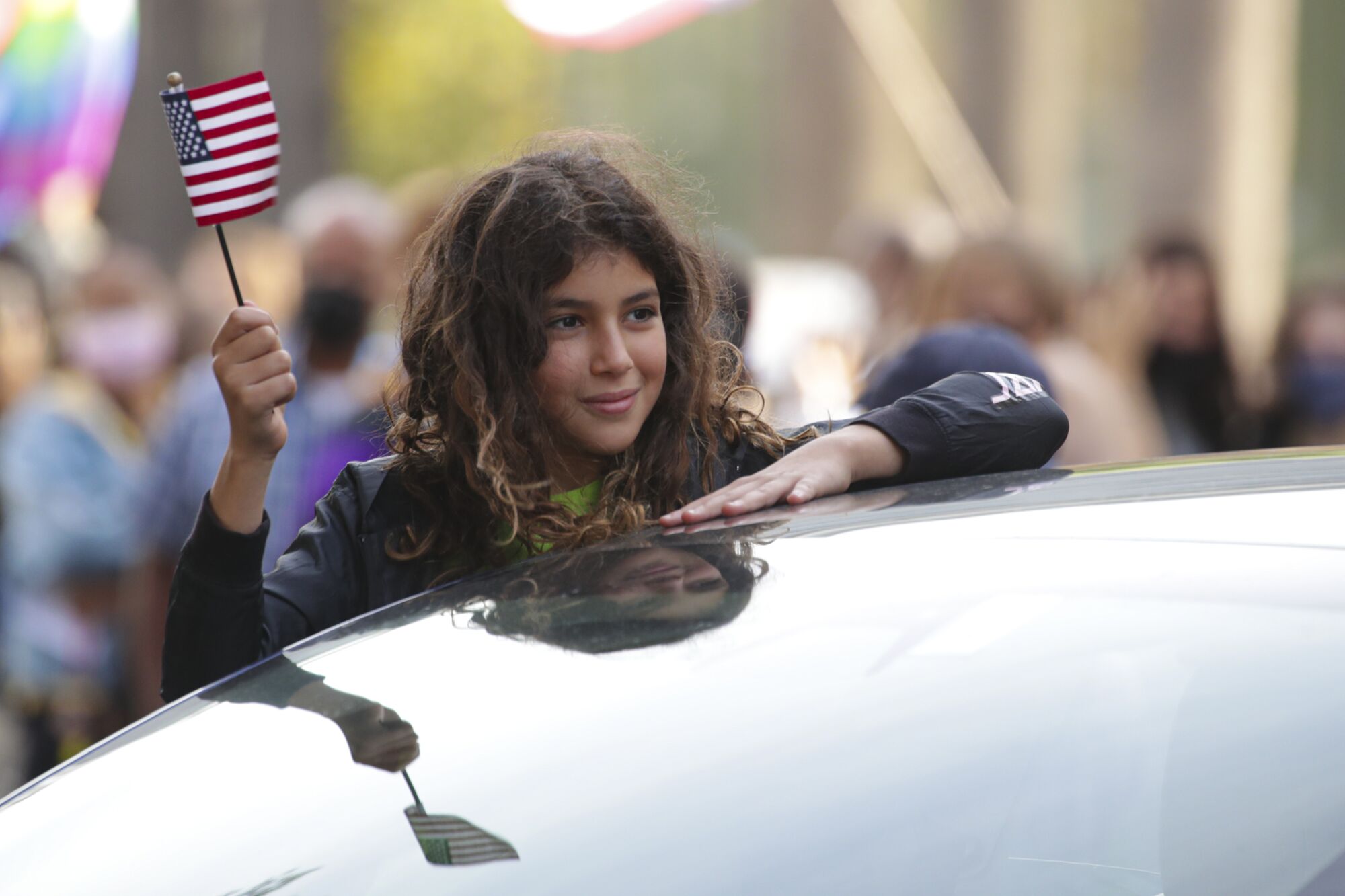A girl holds a mini-American flag.