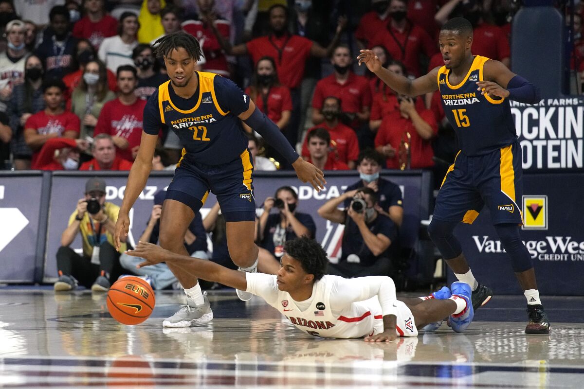 Arizona guard Justin Kier (5) dives for the loose ball in front of Northern Arizona's Wynton Brown (22) and Jalen Cone (15) during the first half of an NCAA college basketball game, Tuesday, Nov. 9, 2021, in Tucson, Ariz. (AP Photo/Rick Scuteri)