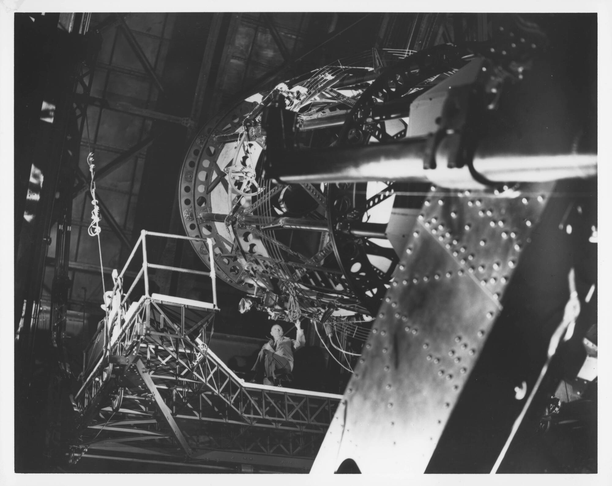 Edwin Hubble sits on the Newtonian platform of the 100-inch reflecting telescope at Mt. Wilson Observatory circa 1940.