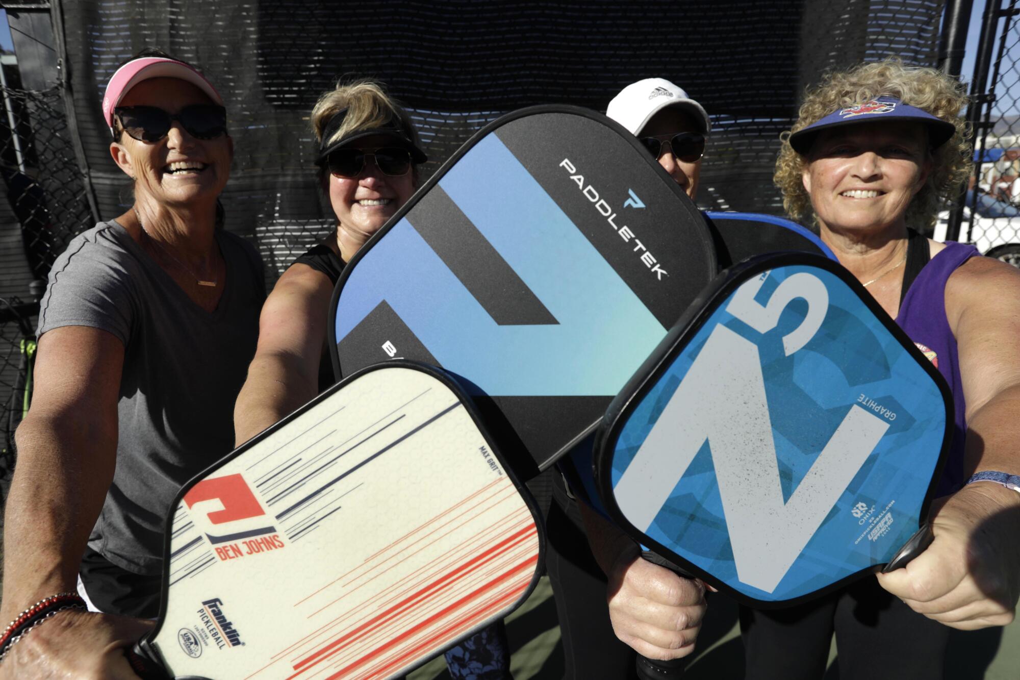Pickleball players pose for a photo, holding up their paddles
