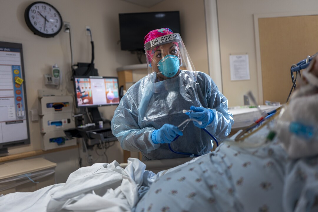 A doctor uses her stethoscope as she examines a patient in bed.