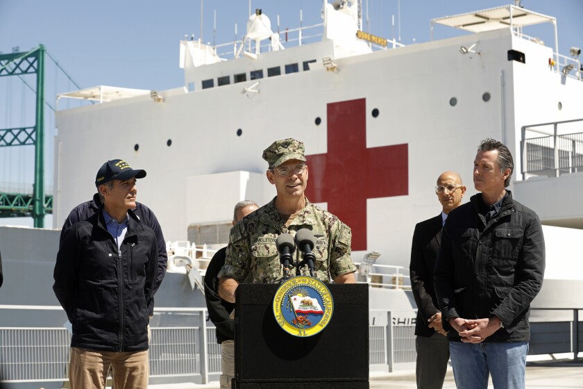 Los Angeles Mayor Eric Garcetti, left, and California Gov. Gavin Newsom, right, listen as Navy Adm. John Gumbleton speaks in front of the hospital ship Mercy that arrived in the Port of Los Angeles on Friday.