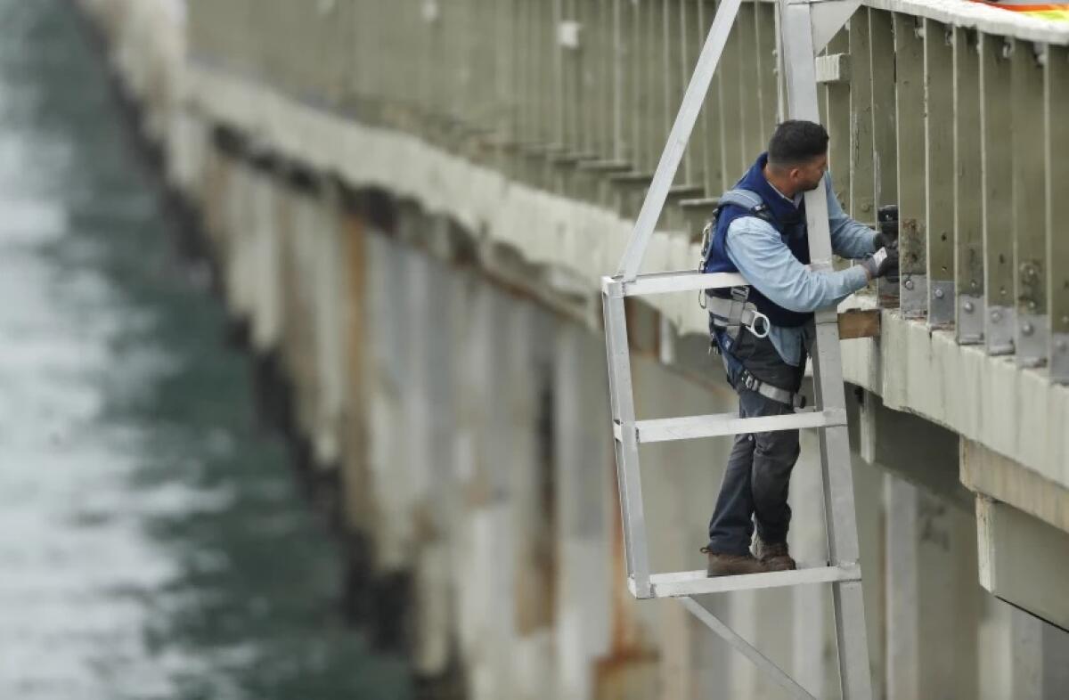 A San Diego city worker makes repairs on the Ocean Beach Pier in May.