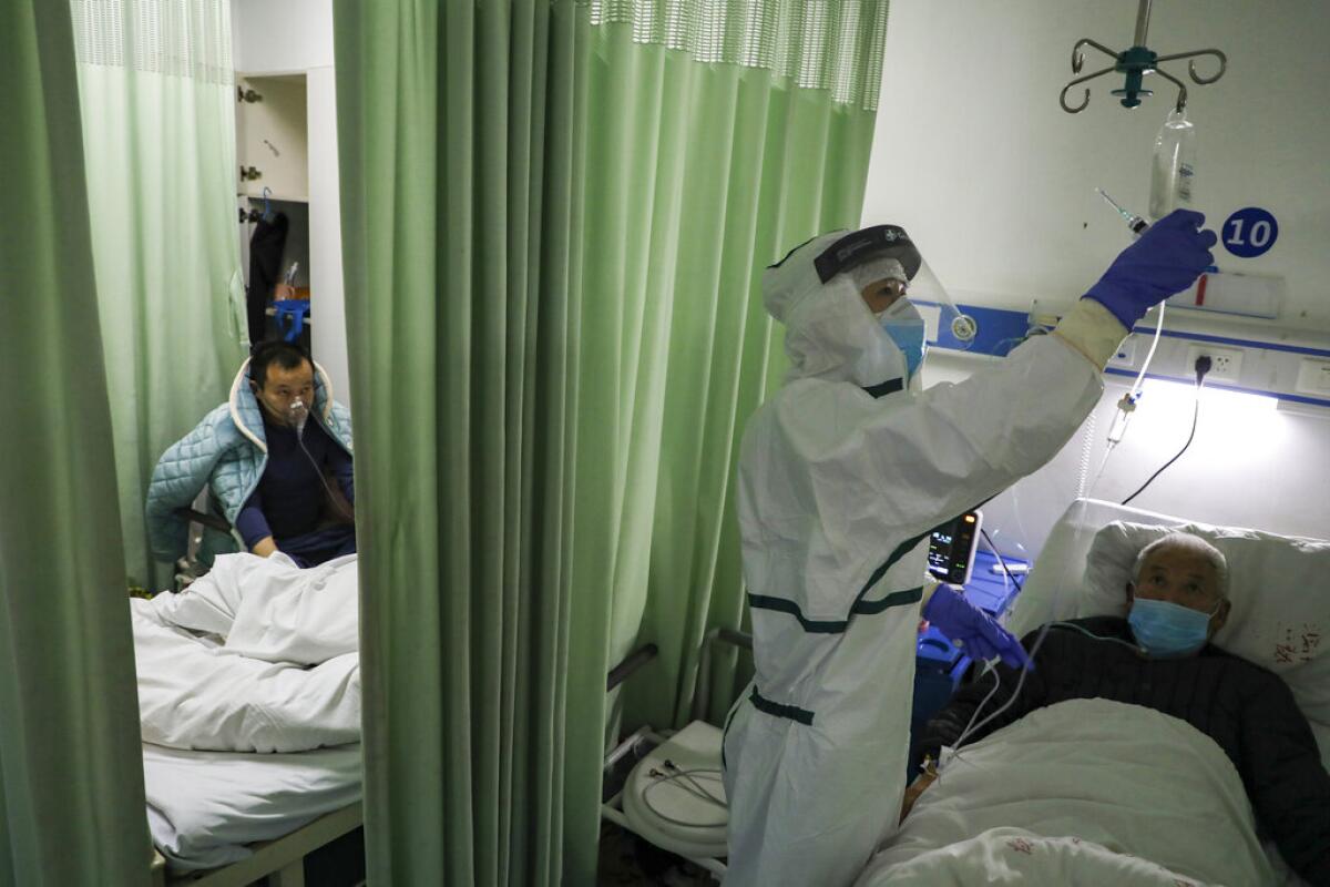 En esta imagen del jueves 6 de febrero de 2020, una enfermera comprueba el estado de un adulto mayor en un ala de aislamiento para pacientes del 2019-nCoV en un hospital de Wuhan, en la provincia china de Hubei. (Chinatopix via AP)