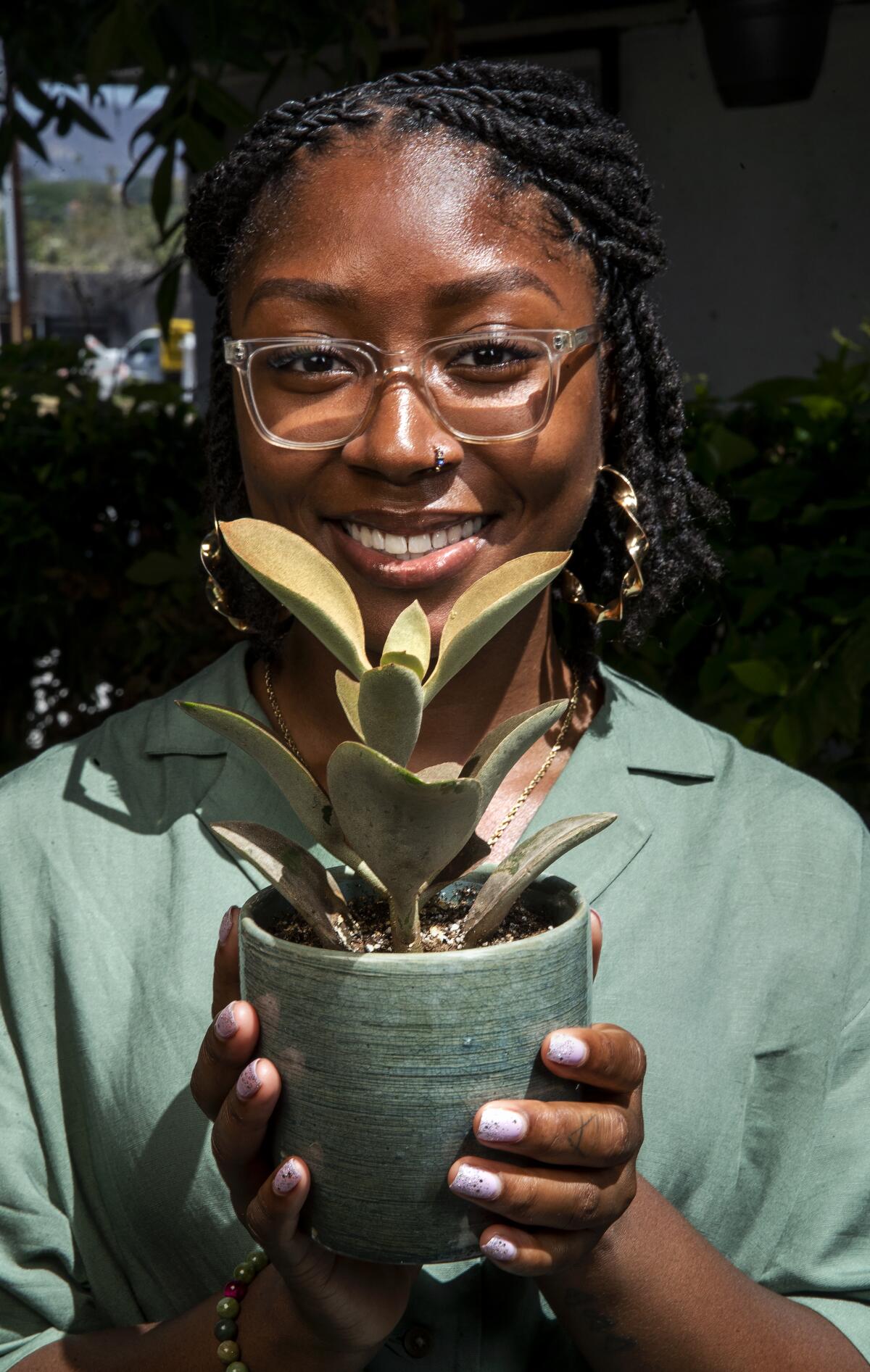 A woman holds a potted plant.