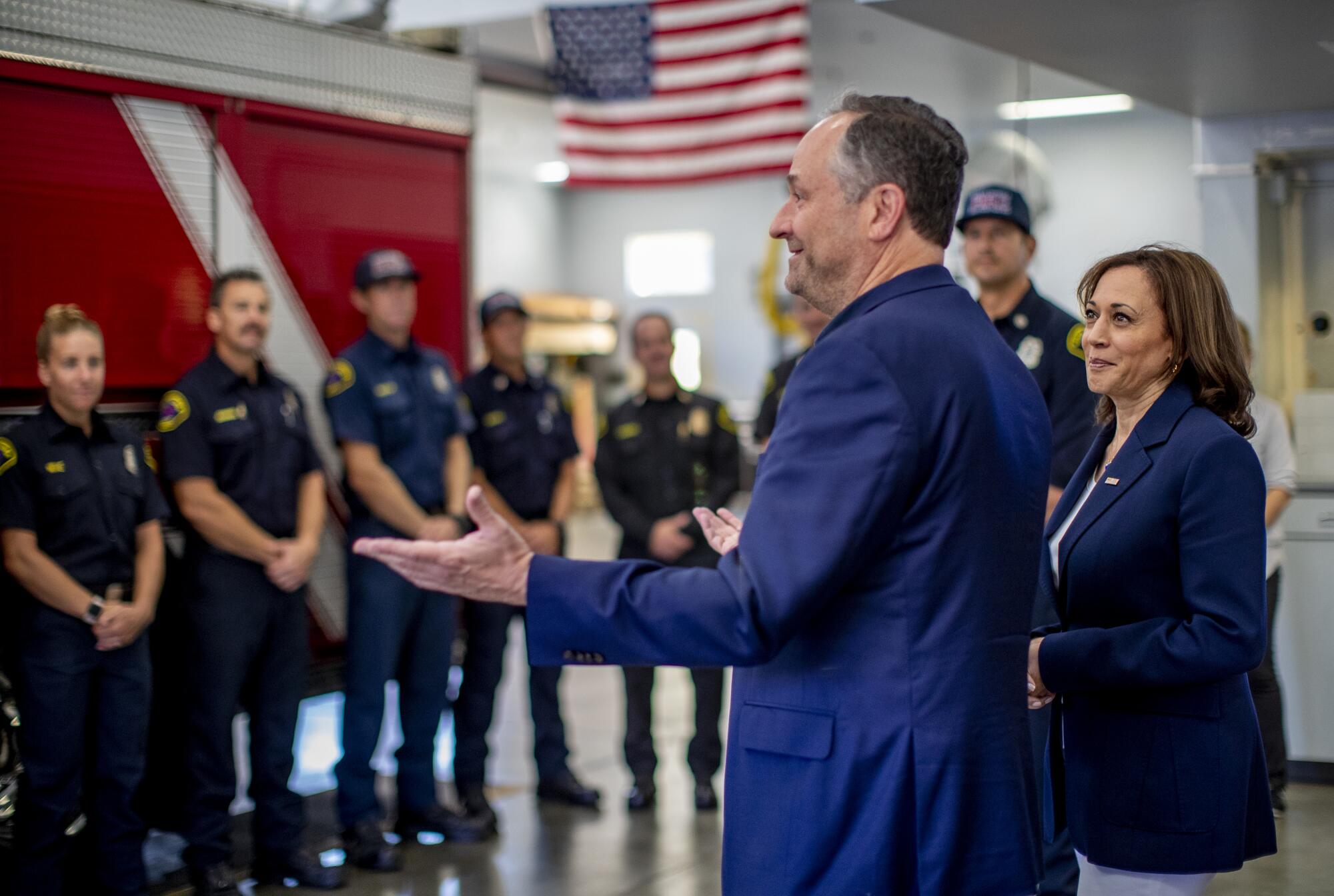 Vice President Kamala Harris listens as Second Gentleman Doug Emhoff speaks to firefighters.