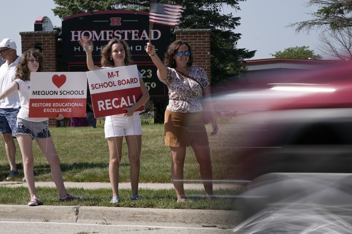 Supporters to recall the entire Mequon-Thiensville School District board wave at cars outside Homestead High School Monday, Aug. 23, 2021, in Mequon, Wis. A loose network of conservative groups with ties to major Republican donors and party-aligned think tanks is quietly lending firepower to local activists engaged in the culture war fights in schools across the country. (AP Photo/Morry Gash)