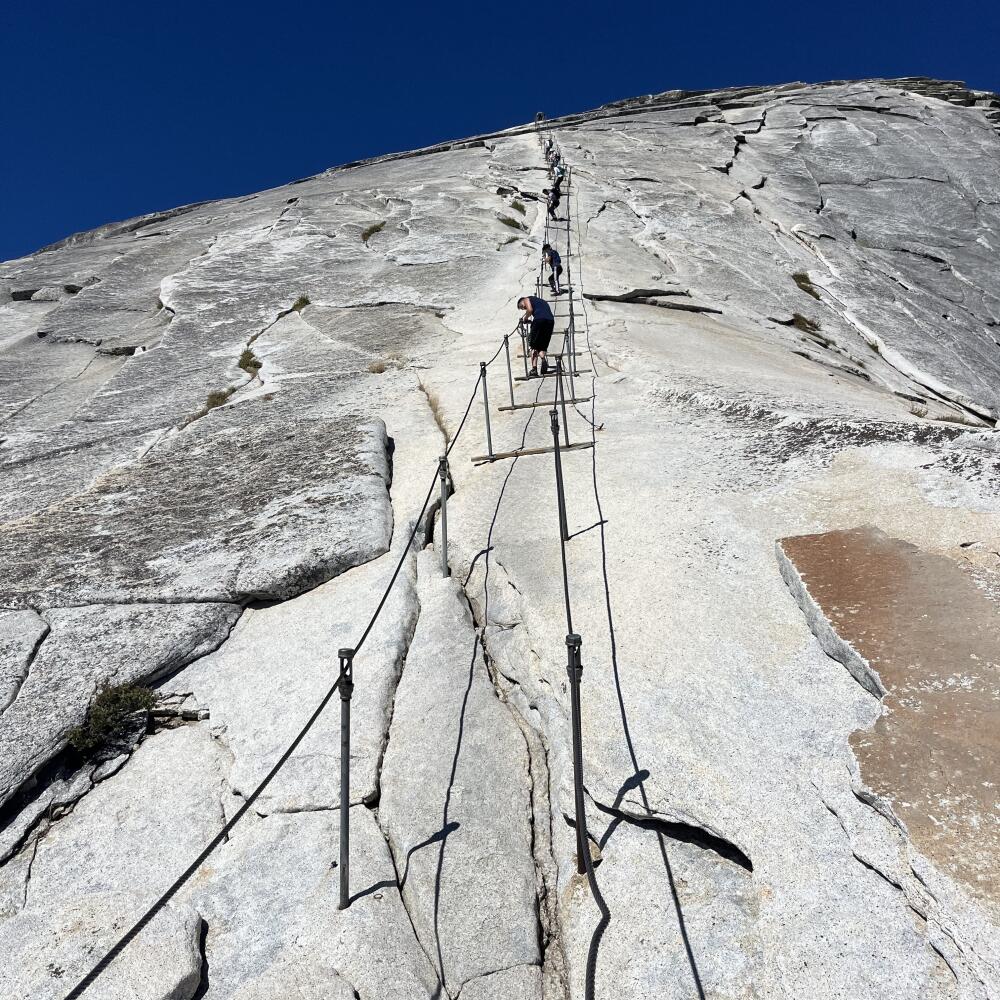 Steel cables span the steep final ascent across granite to Half Dome's summit. 