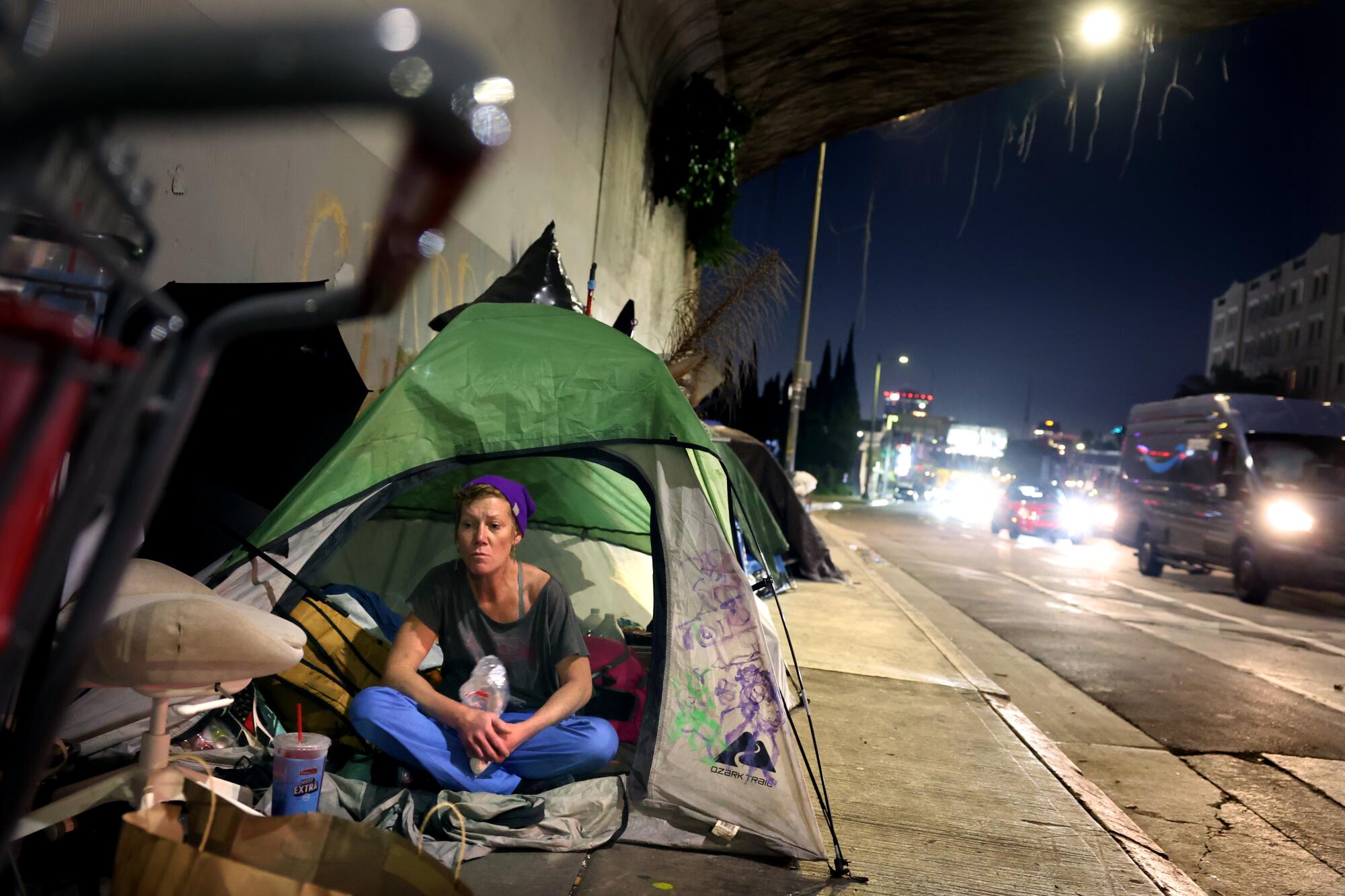 A homeless woman eats marshmallows at a homeless encampment under the 101 Freeway in Hollywood.