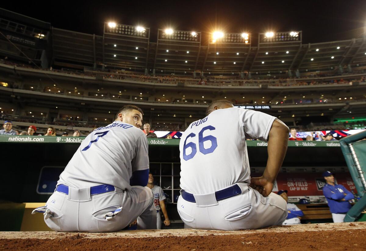 Dodgers utility player Alex Guerrero (7) and right fielder Yasiel Puig (66) sit on the edge of the dugout at Nationals Park, where a bank of lights malfunctioned three times on Friday night.