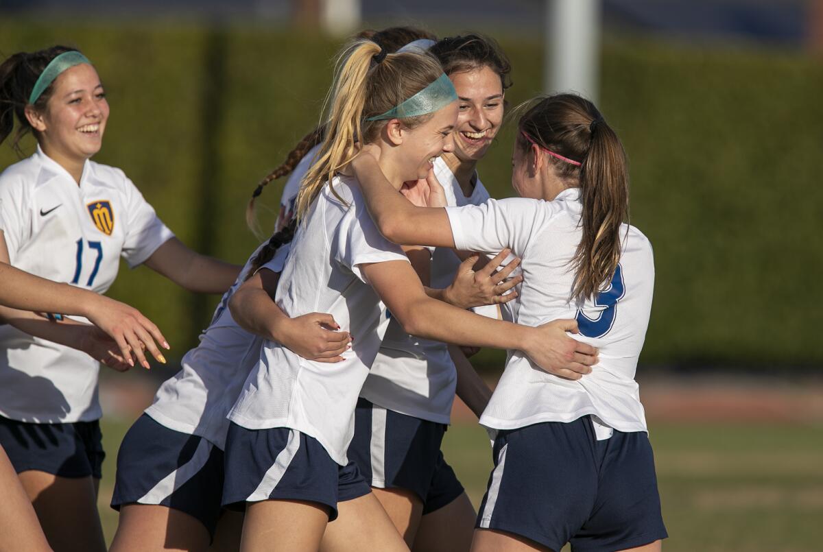 Marina's Kendall Crosby is mugged by her teammates after scoring a goal against Bishop Amat on Friday.