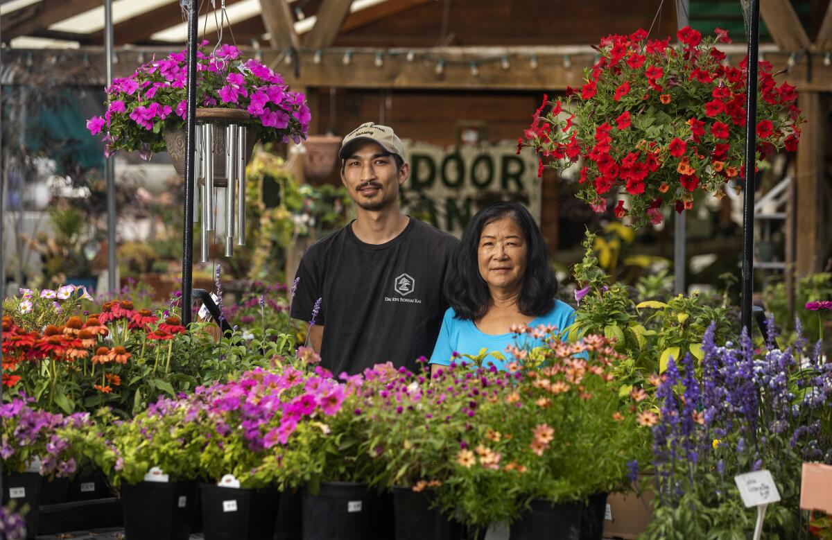 A man and woman stand among pots of flowers 