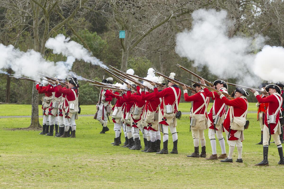 Members of the British army fire during an American Revolutionary War reenactment in Huntington Beach in 2018. Another will be held Saturday and Sunday at Huntington Beach's Central Park.