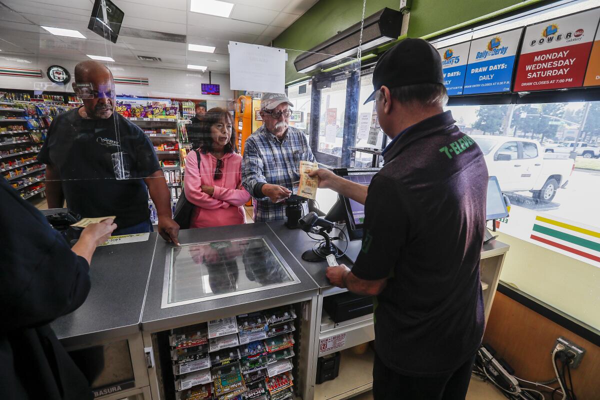 A cashier hands a lottery ticket to customers.