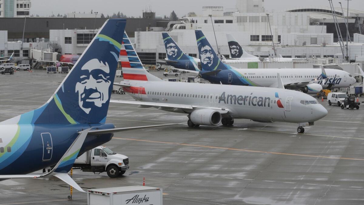 An American Airlines plane taxis past Alaska Airlines airplanes at the Seattle-Tacoma International Airport. Alaska Airlines plans to close its pilot base in New York.