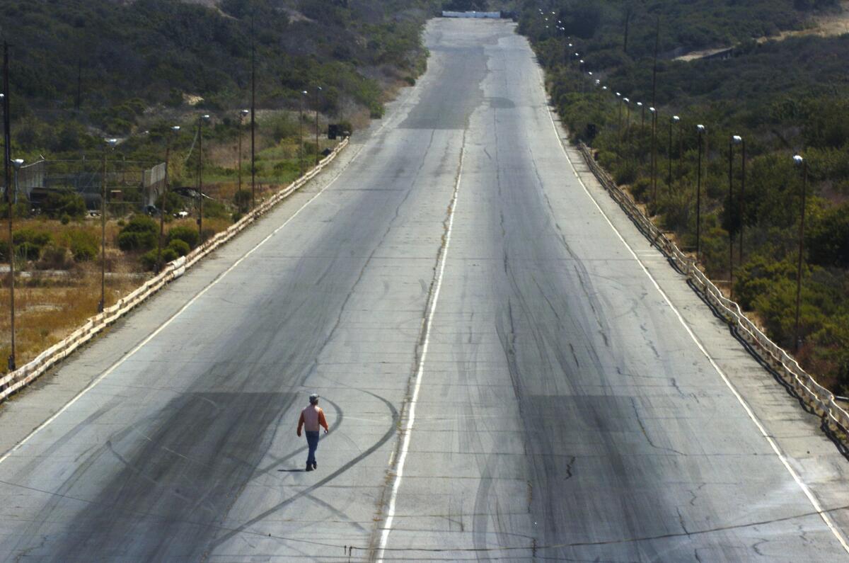 A construction surveyor walks the 1/4-mile drag strip after the closure of the Carlsbad Raceway in 2004. a 