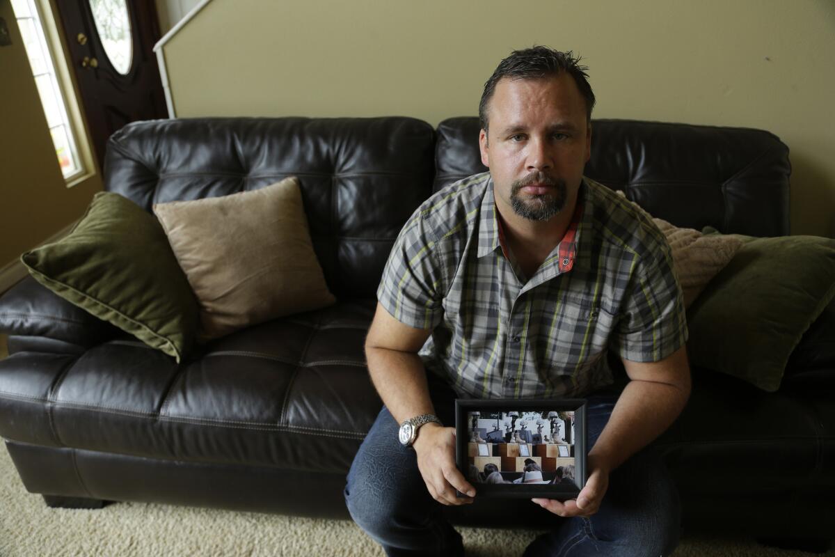 Retired U.S. Army Staff Sgt. Shawn Manning, at his home in Lacey, Wash., holds a photograph from a memorial for victims of a 2009 mass shooting at Ft. Hood, Texas. Manning, who still carries two bullets in his body from the shooting that killed 13 people, testified against Maj. Nidal Malik Hasan, the accused shooter.