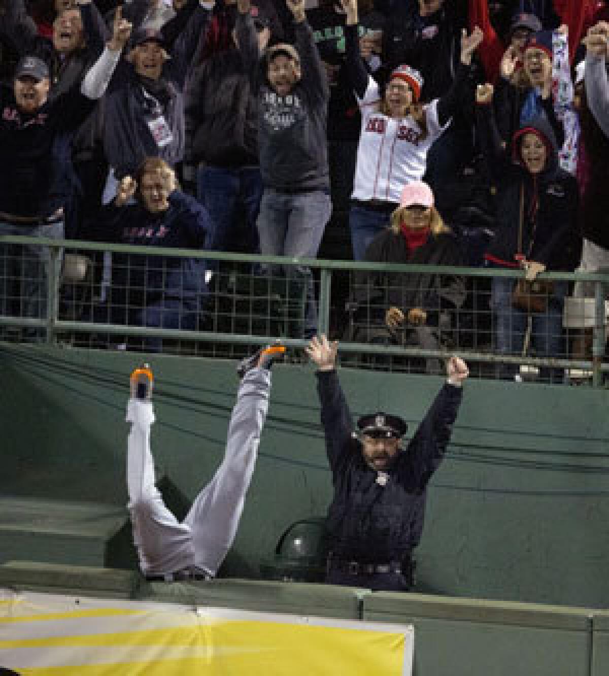 Fans and Boston Police officer Steve Horgan celebrate as Detroit Tigers' Torii Hunter falls over the right field fence into the bullpen trying to catch a grand slam hit by David Ortiz during Game 2.
