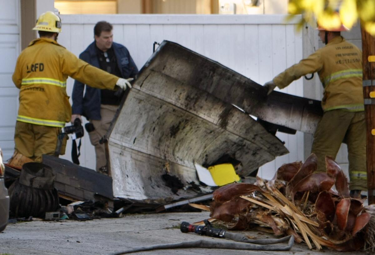 Investigators look over damaged pieces of the garage where the man's body was discovered.