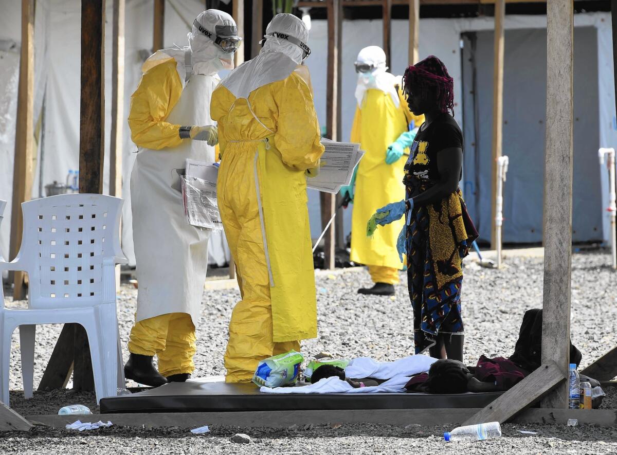 Health workers tend to a woman with two children this month at a Doctors Without Borders Ebola treatment center in Monrovia, Liberia. The group is the biggest Ebola treatment provider in West Africa.