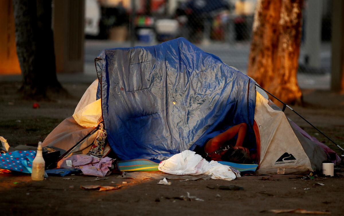 A woman sleeps in a tent as the sun sets on MacArthur Park in Los Angeles on Friday.