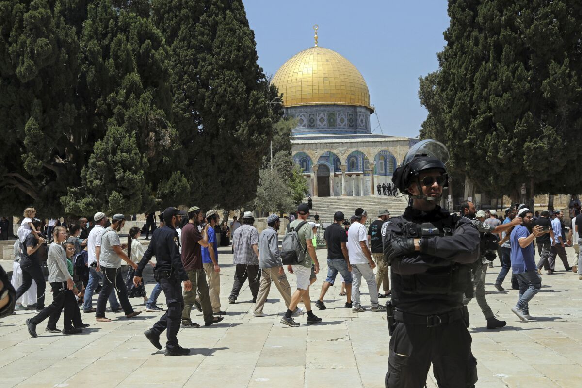 An Israeli police officer stands guard as Jewish men visit the Dome of the Rock Mosque in the Al Aqsa Mosque compound, during the annual mourning ritual of Tisha B'Av (the ninth of Av) -- a day of fasting and a memorial day, commemorating the destruction of ancient Jerusalem temples, in the Old City of Jerusalem, Sunday, July 18, 2021. (AP Photo/Mahmoud Illean)