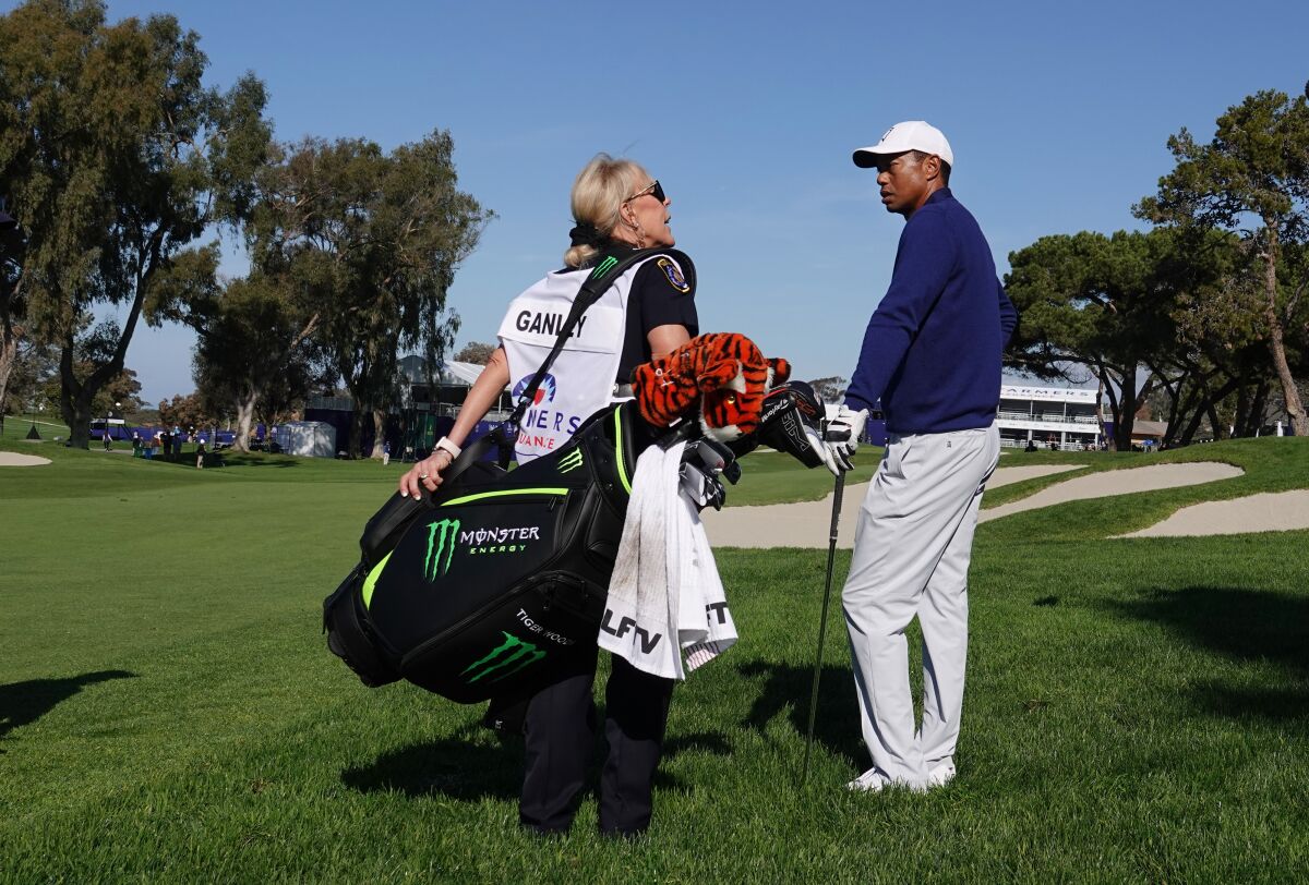 San Diego Police officer Debbie Ganley caddies for Tiger Woods on the 18th hole of Torrey Pines South Course during the Farmers Insurance Open Pro-Am on Wednesday.