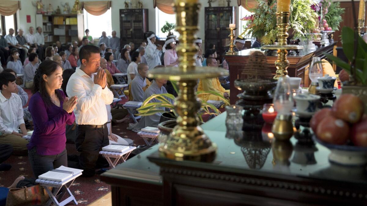 Dieu Ho, left, and Hoai Le pray for son Tommy Le at his reincarnation ceremony in August..