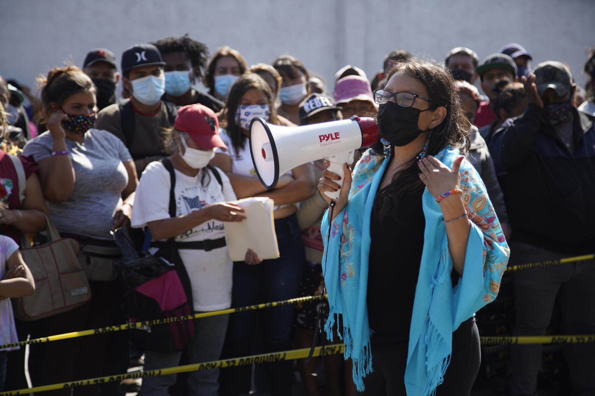 A woman with a megaphone speaks to a group of people.