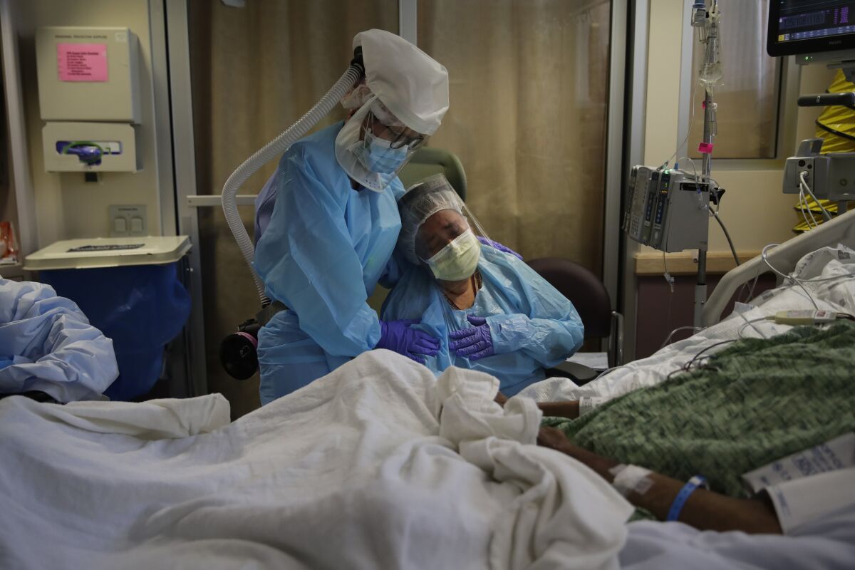 A nurse comforts a grieving woman in St. Jude Medical Center's COVID-19 unit in Fullerton. 