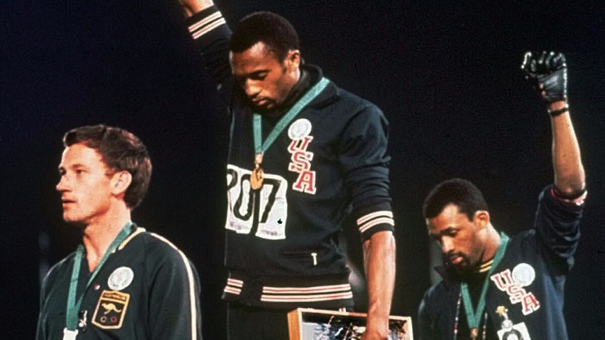 U.S. athletes Tommie Smith, center, and John Carlos, right, raise their fists on the podium at the 1968 Mexico City Games. Under updated guidelines, such a gesture will not be allowed on the podium.