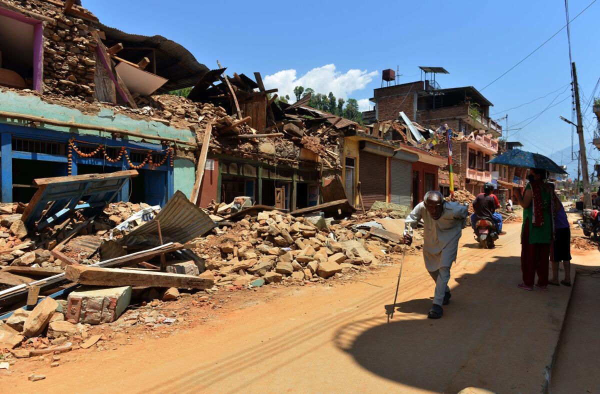 Nepalese people walk past damaged houses in Nuwakot district north of Katmandu on Monday. The earthquake death toll has risen to more than 7,200 with some 14,000 injured.