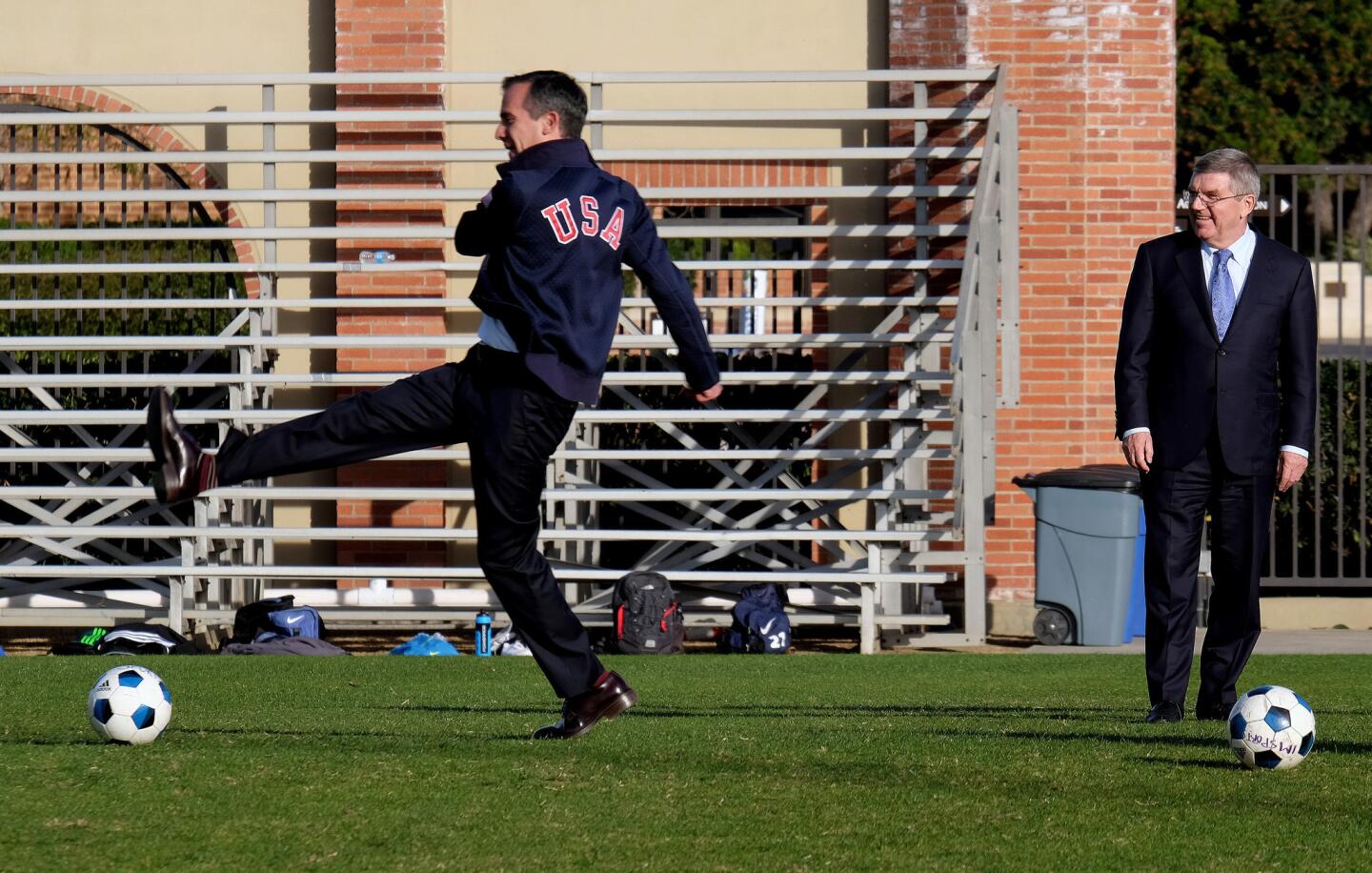 Thomas Bach, right, president of the International Olympic Committee, watches as Los Angeles Mayor Eric Garcetti, left, kicks a soccer ball prior to a news conference at UCLA, Monday, Feb. 1, 2016. Bach is visiting Los Angeles to check out proposed venues for the 2024 Olympic Games. Thomas Bach's visit to the University of Southern California and UCLA campuses, as well as the Getty Center. (AP Photo/Richard Vogel)