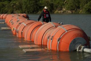 FILE - A kayaker walks past large buoys being used as a floating border barrier on the Rio Grande, Aug. 1, 2023, in Eagle Pass, Texas. A federal judge on Wednesday, Sept. 6, ordered Texas to move a large floating barrier to the riverbank of the Rio Grande after protests from the the U.S. and Mexican governments over Republican Gov. Greg Abbott’s latest tactic to stop migrants from crossing America’s southern border. (AP Photo/Eric Gay, File)