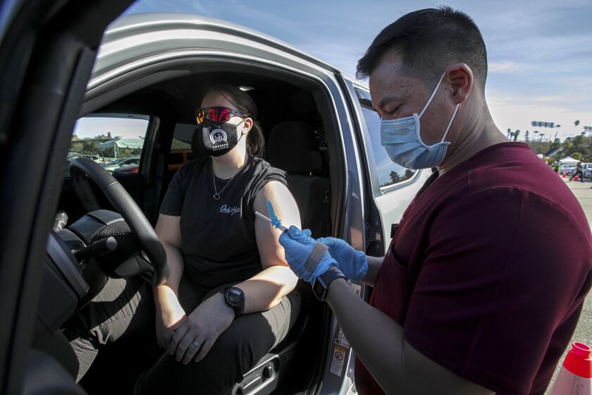 Los Angeles, CA - January 15: Dr. Richard Dang, right, Assistant professor USC School of Pharmacy administers COVID-19 vaccine to Ashley Van Dyke as mass-vaccination of healthcare workers takes place at Dodger Stadium on Friday, Jan. 15, 2021 in Los Angeles, CA. (Irfan Khan / Los Angeles Times)