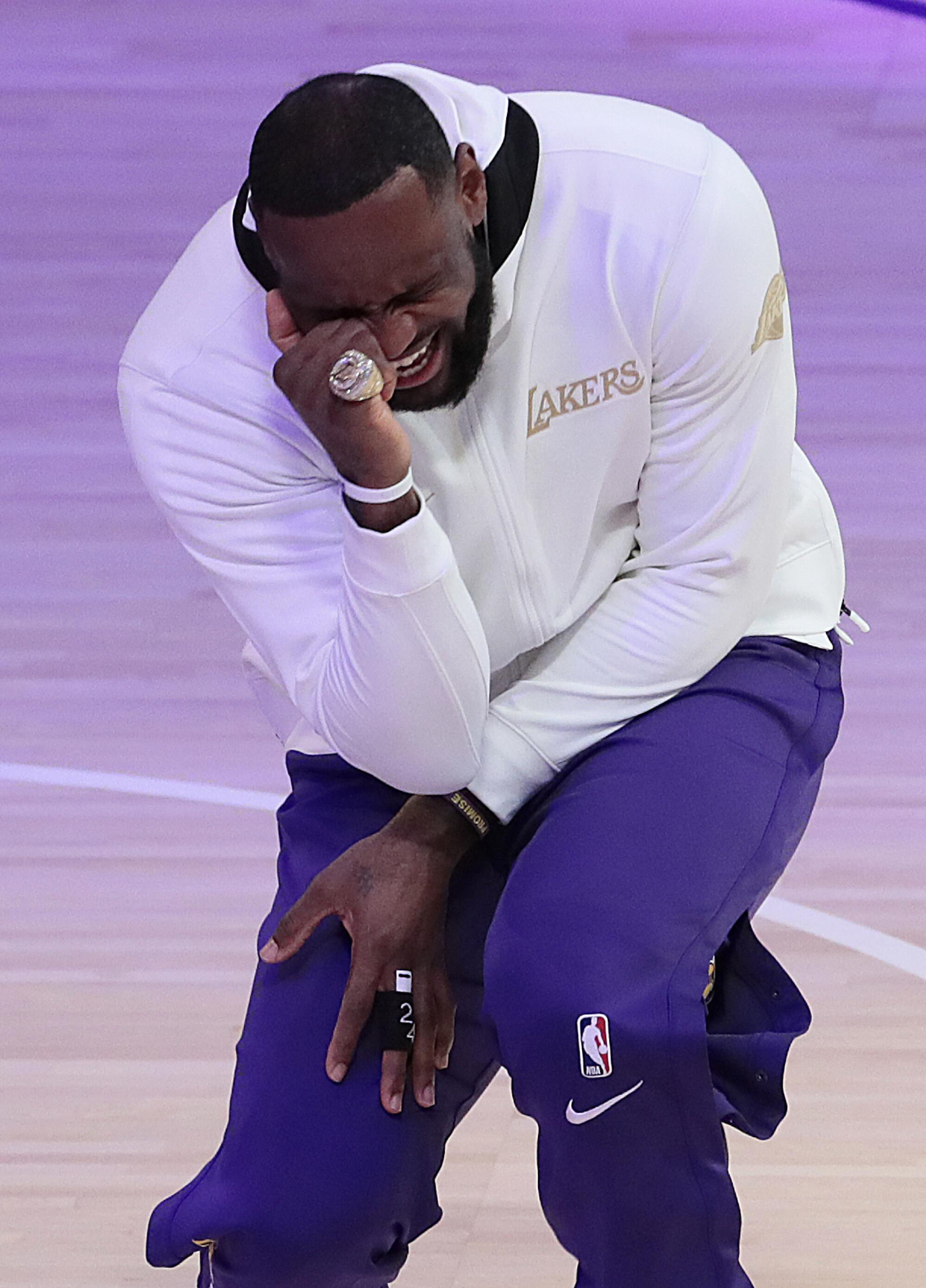 Lakers forward LeBron James kneels on the court after receiving his 2020 NBA championship ring.