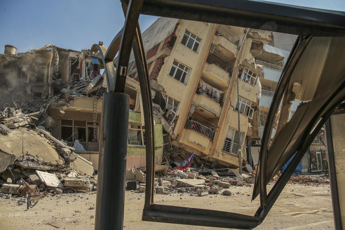 A destroyed building leans on a neighboring house following the recent earthquake in Samandag, Turkey.