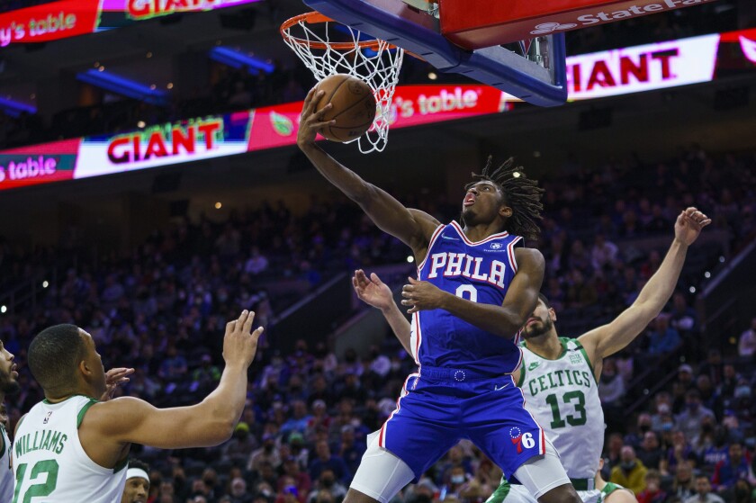 Philadelphia 76ers' Tyrese Maxey, center, goes up to shoot as he gets past Boston Celtics' Enes Freedom, right, during the first half of an NBA basketball game, Friday, Jan. 14, 2022, in Philadelphia. (AP Photo/Chris Szagola)