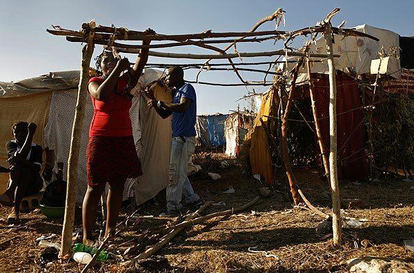 Esther Devariste, 21, and Ernest St. Pruce, 25, tie sticks together to make a small tent for their family at a camp in the Delmas area of Port-au-Prince, Haiti.