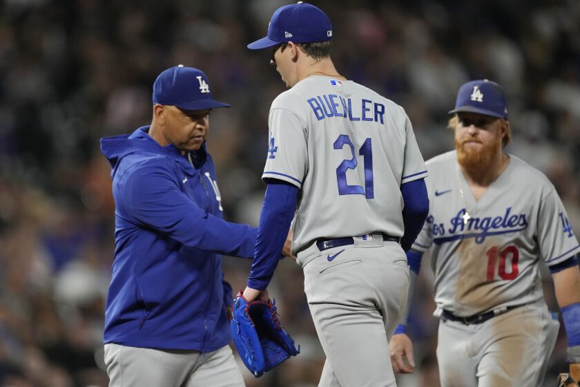 Los Angeles Dodgers manager Dave Roberts, left, takes the ball from starting pitcher Walker Buehler as he leaves the mound after giving up a two-run double to Colorado Rockies' German Marquez in the fourth inning of a baseball game Wednesday, Sept. 22, 2021, in Denver. Los Angeles third baseman Justin Turner, right, looks on. (AP Photo/David Zalubowski)